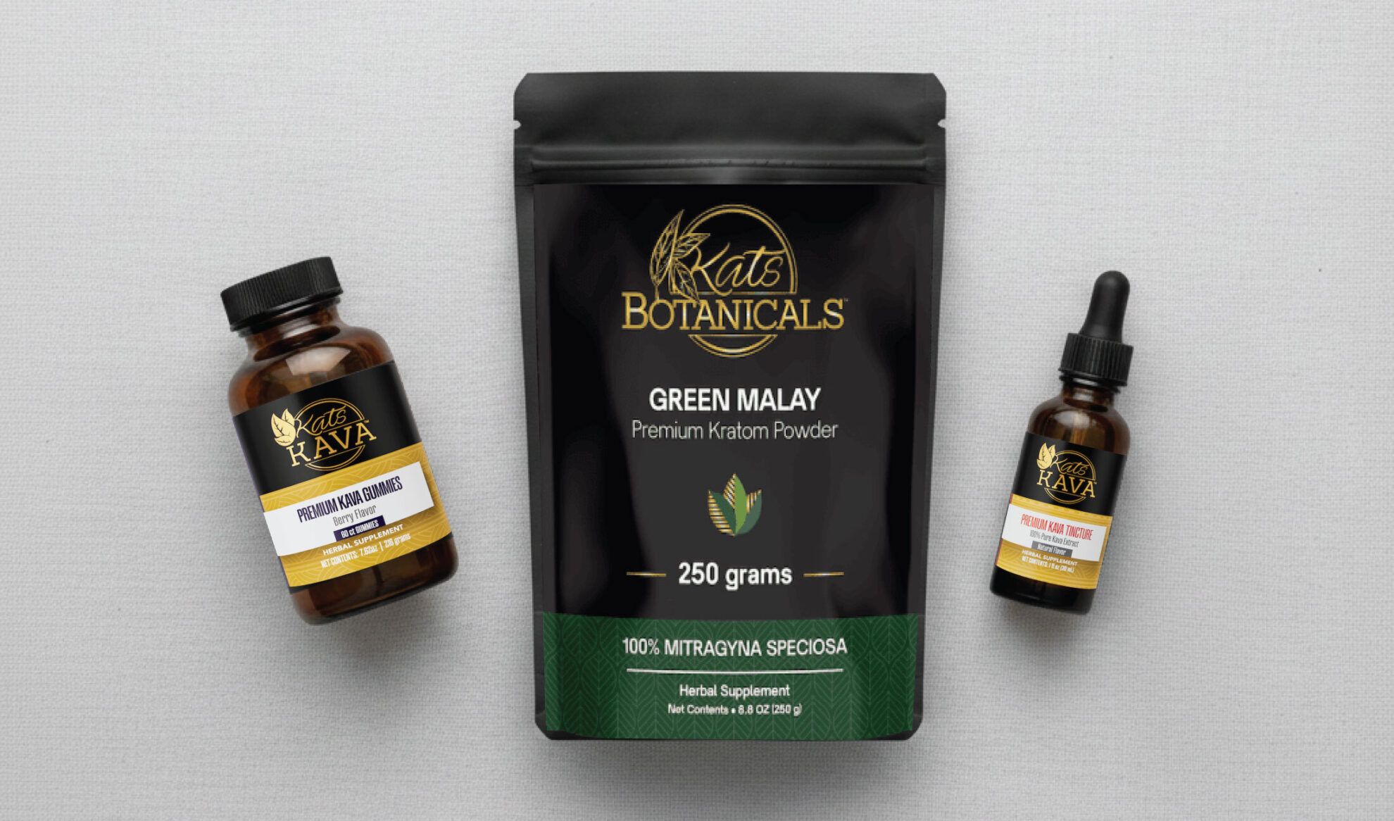 Three Kats Botanicals products are displayed: a bottle labeled Premium Canine, a large pouch of Green Malay Premium Kratom Powder, and a dropper bottle labeled Premium Kava, all on a light gray surface.