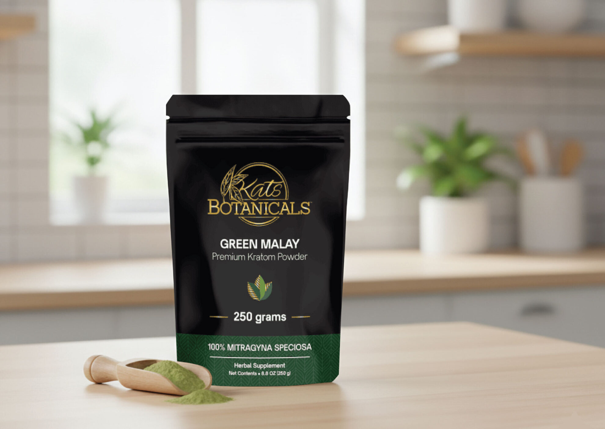 A black bag labeled Kats Botanicals Green Malay Premium Kratom Powder, 250 grams stands on a kitchen counter with a wooden scoop and spilled green powder nearby. The background shows blurred kitchen shelves and a window.