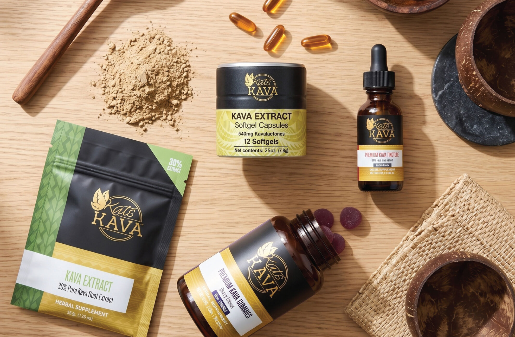 A selection of Kat’s Kava products, including capsules, powder, tincture, extract, and gummies, arranged on a wooden surface with bowls and a wooden spoon.